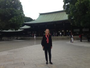 Profesor Pałasz Rutkowska w Japonii. Szczupła blondynka w ciemnych ubraniach, w tle tradycyjna budowla japońska z ciemnozielonym dachem